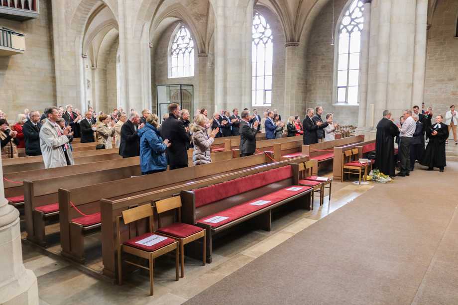 Menschen applaudieren stehend in einer Kirche.